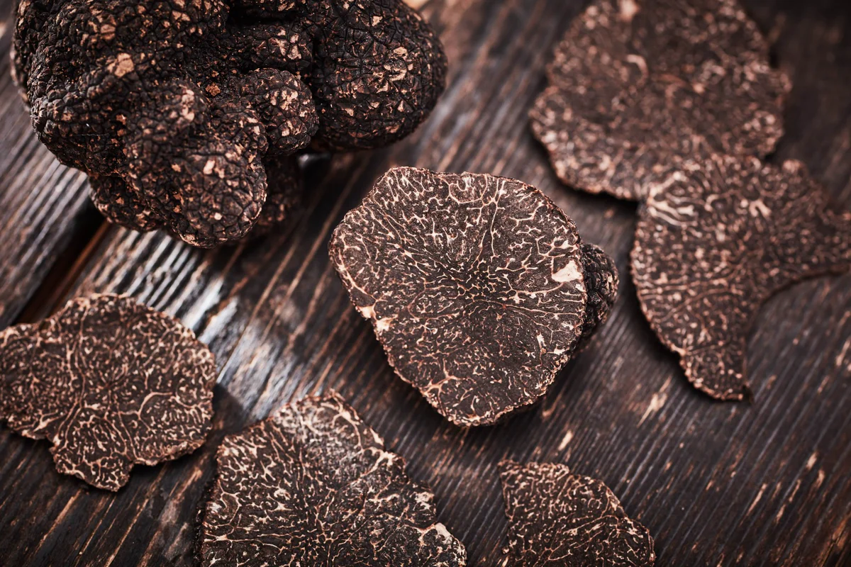 Whole black truffles on a wooden board with grater